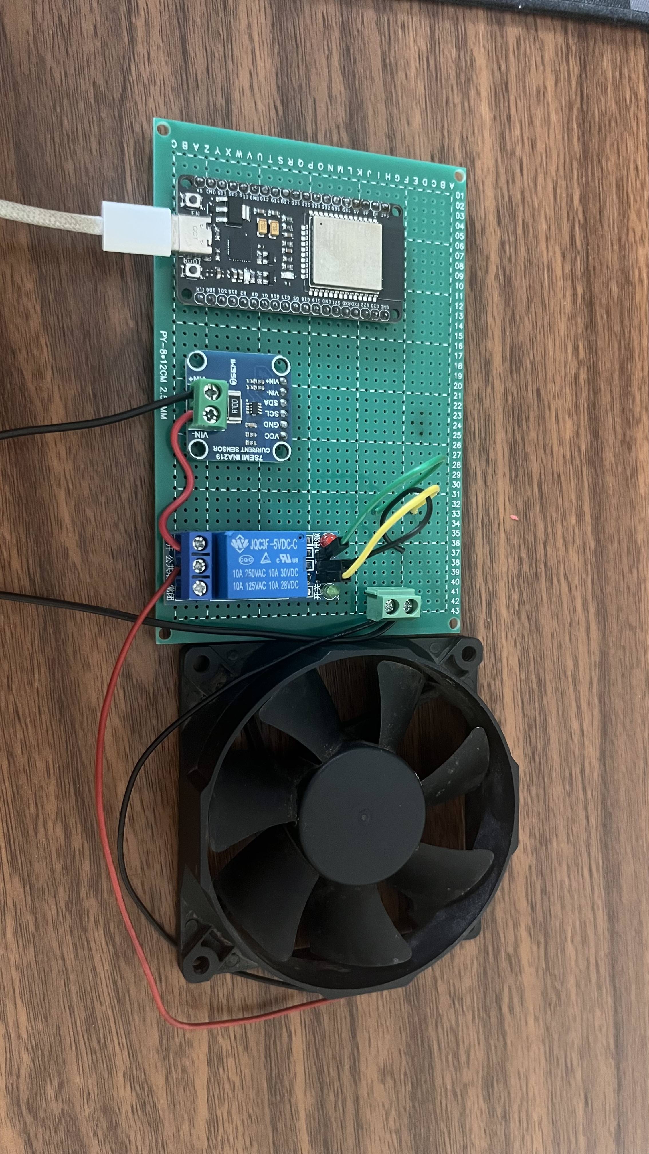 Real-world setup: ESP32 wired to the INA219 and relay module on a veroboard, with the phone charger powering the load through the relay contacts.
